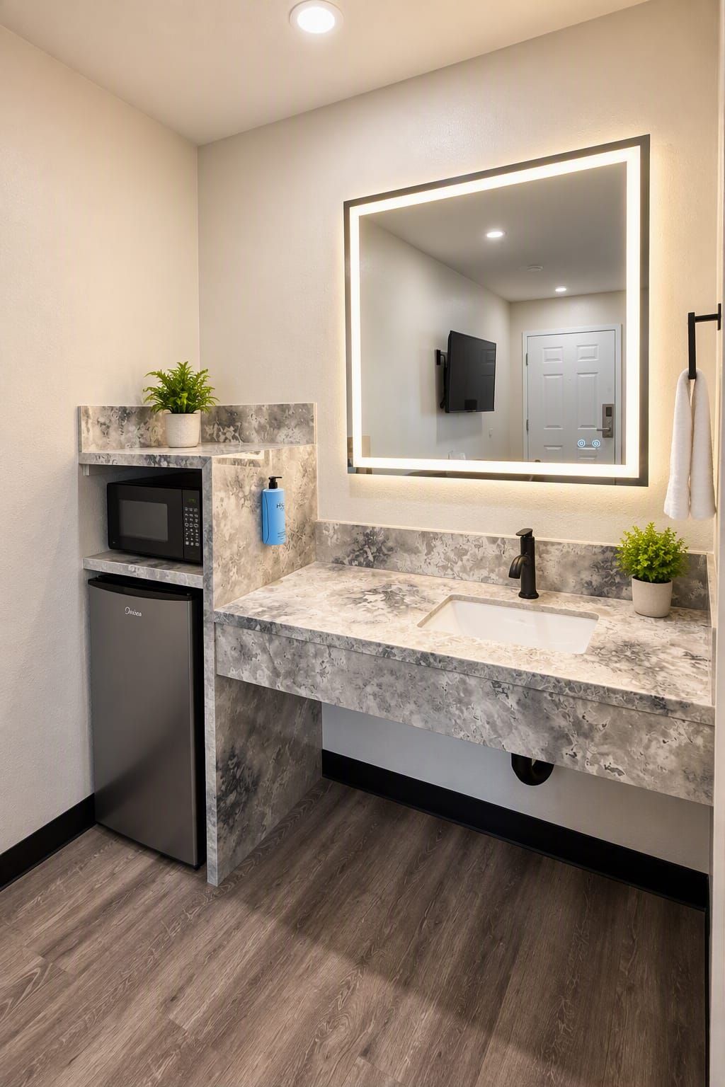 A modern bathroom with a marble countertop, a built-in sink, a microwave, and a small refrigerator.