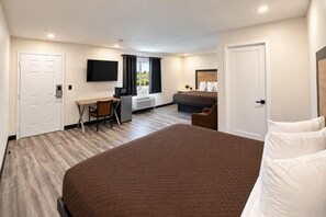 A hotel room with a large bed, a desk with a chair, a television, and a window with curtains. - Rocky Inn Motel (Long Beach)