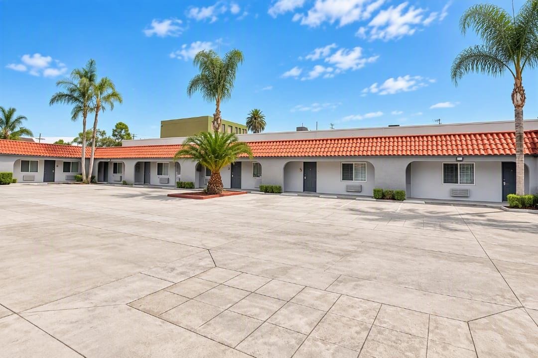 A motel with a courtyard, individual rooms, and a red-tiled roof.