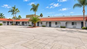 A motel with a courtyard, individual rooms, and a red-tiled roof.