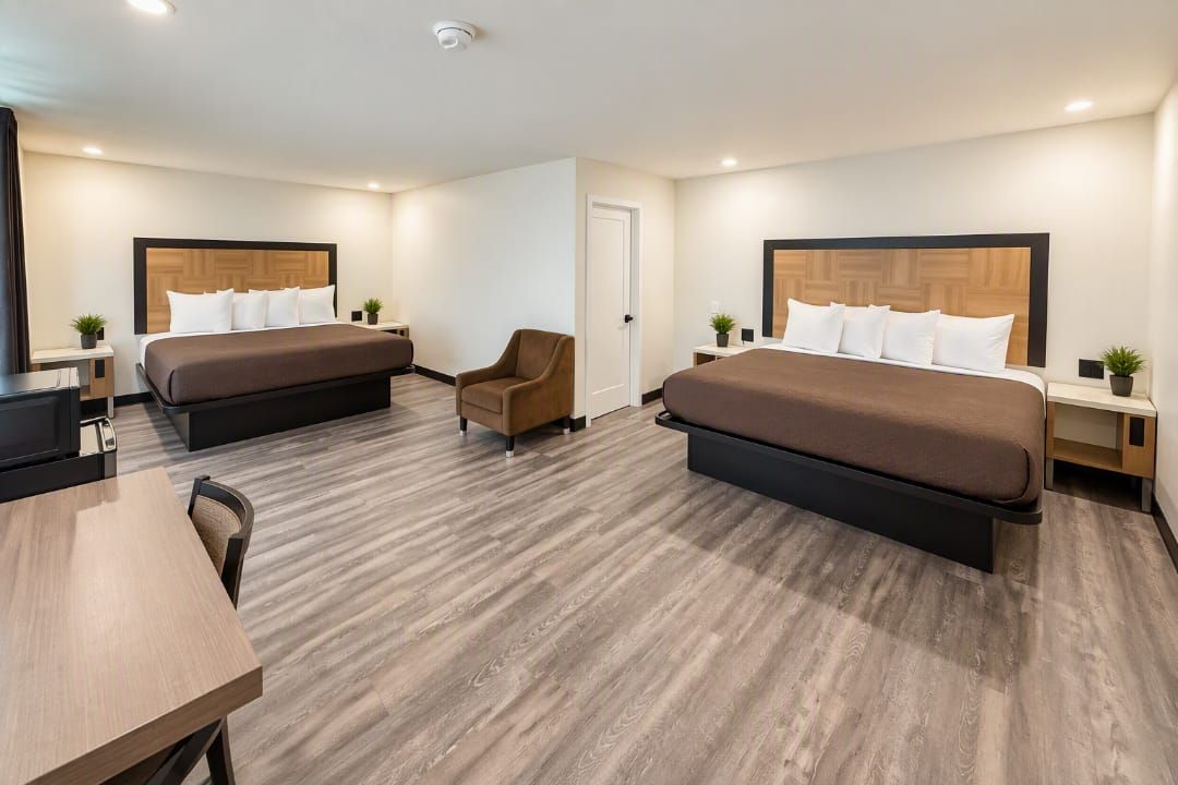 Una habitación de hotel con dos camas, un escritorio, una silla y una mesita.