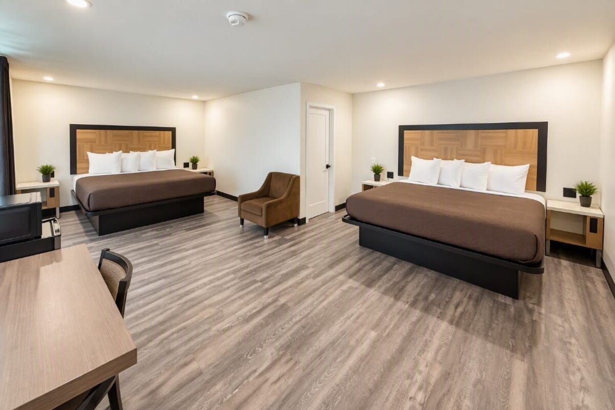 Une chambre d’hôtel avec deux lits, un bureau, une chaise et une petite table.