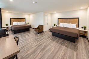 Une chambre d’hôtel avec deux lits, un bureau, une chaise et une petite table.