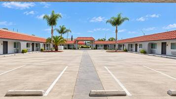A motel with a central courtyard, individual rooms with red-tiled roofs, and palm trees.