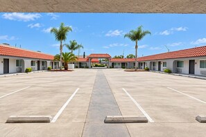 A motel with a central courtyard, individual rooms with red-tiled roofs, and palm trees. - Rocky Inn Motel (Long Beach)