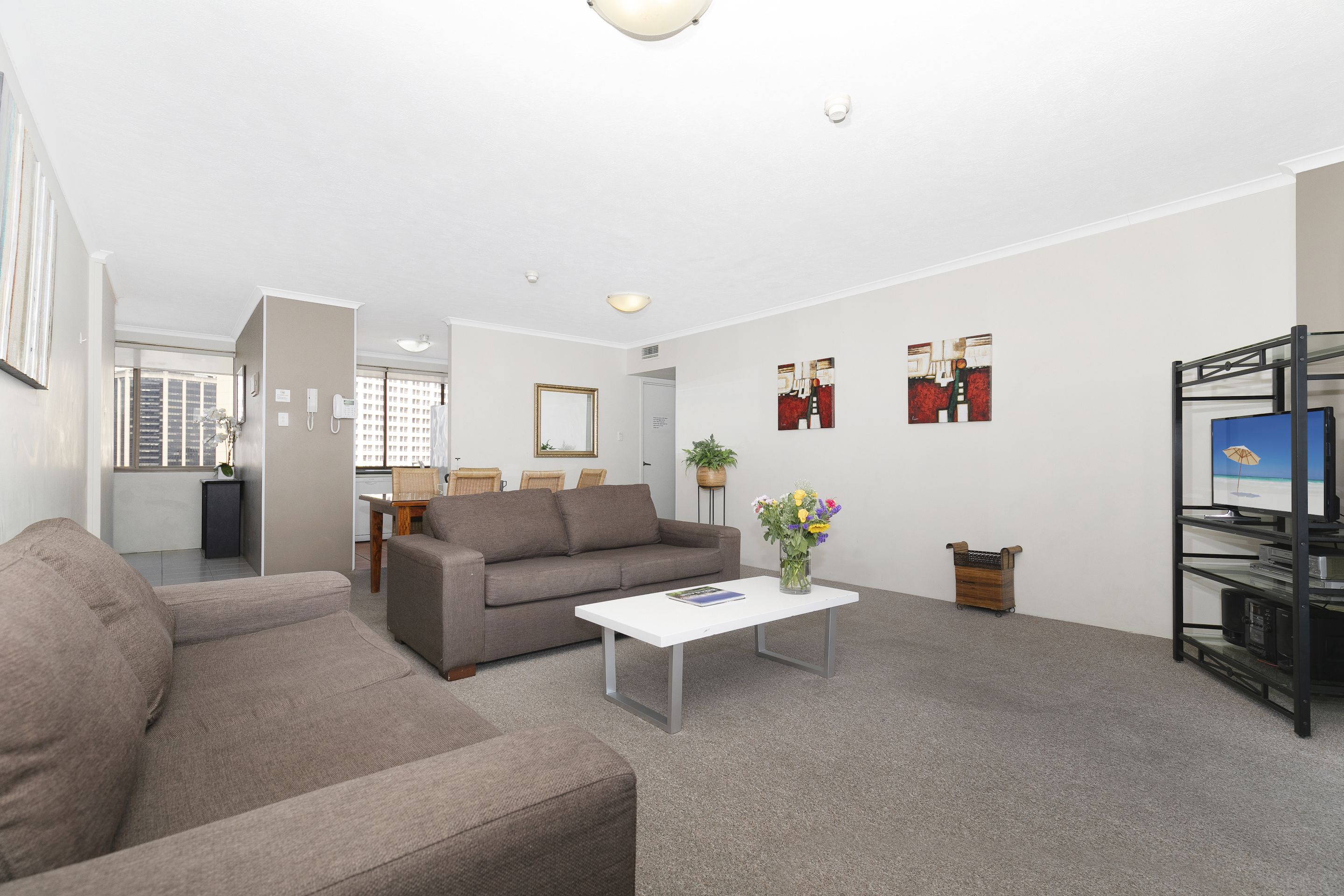 A modern living room with a grey sofa, a white coffee table, and a bookshelf.