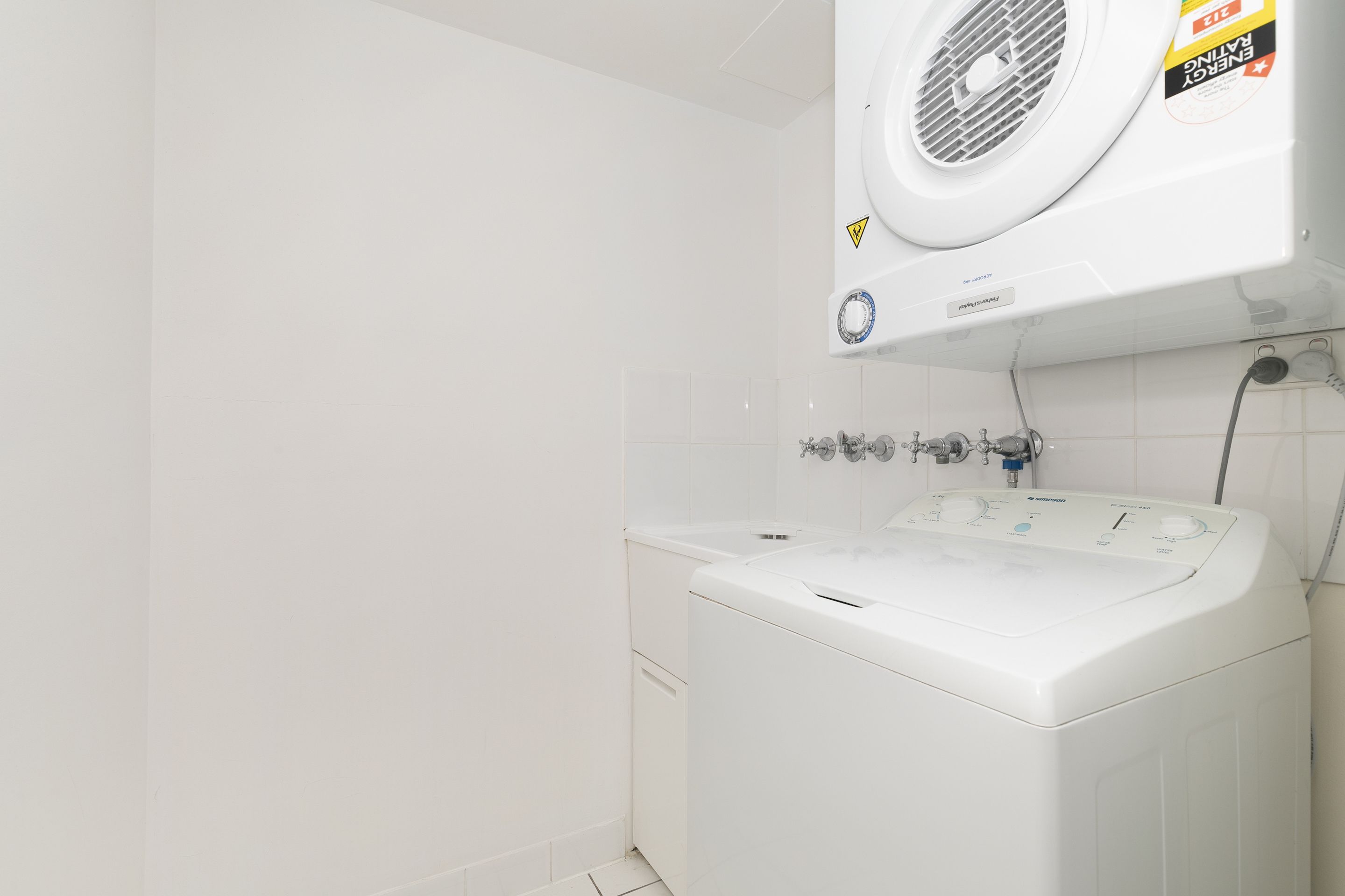 En hvid vaskemaskine med kontrolpanel og ventilationsåbning over.