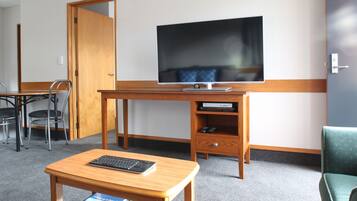 Een hotelkamer met een houten bureau, een televisie, een stoel en een klein tafeltje.