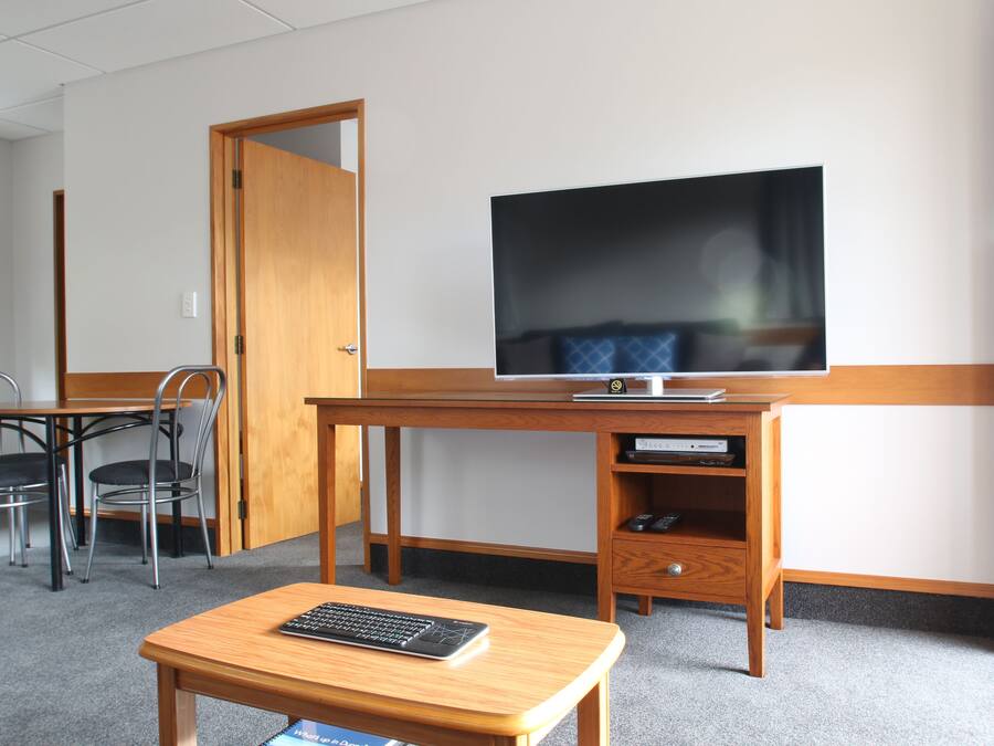 Een hotelkamer met een houten bureau, een televisie, een stoel en een klein tafeltje.