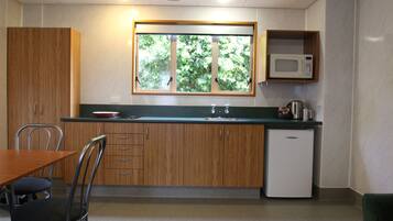 A compact kitchen with wooden cabinets, a built-in microwave, a sink, and a window with a view of greenery.
