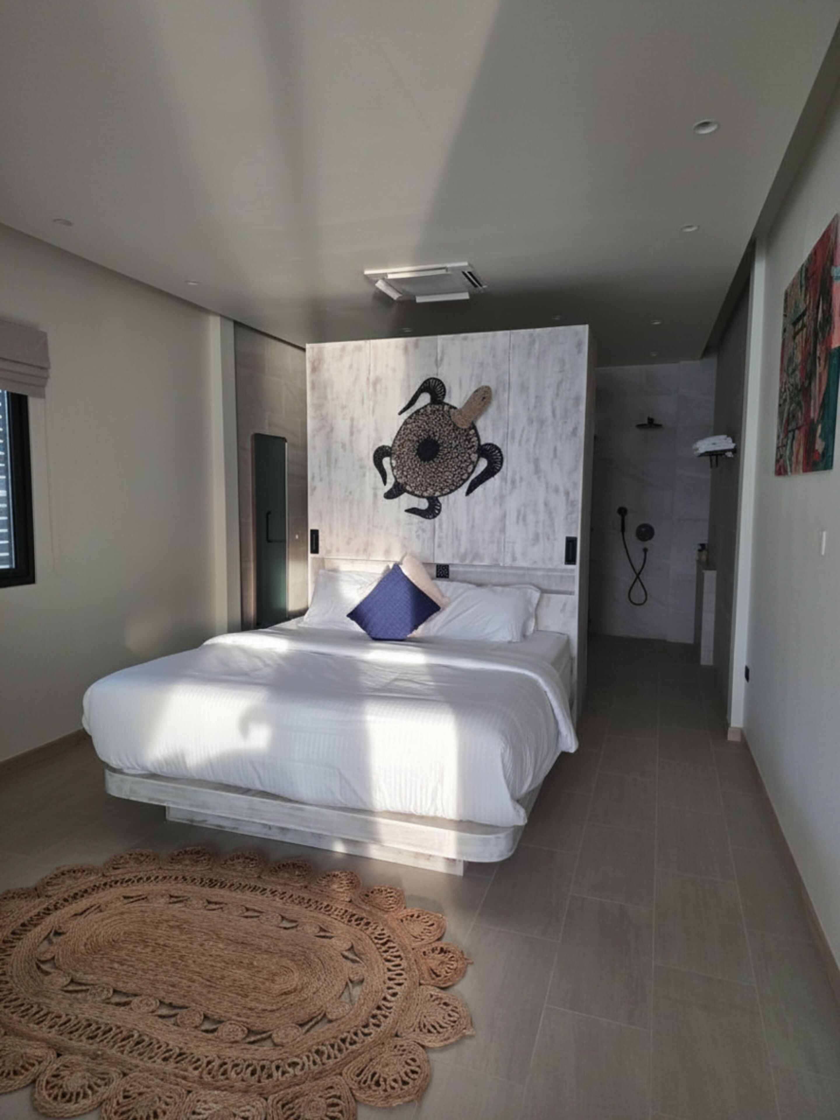 Ein modernes Schlafzimmer mit einem großen Bett, einer Wanddekoration, einer Dusche und einem Teppich.