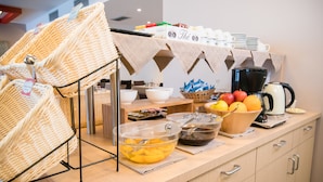 A buffet setup with wicker baskets, bowls of fruit, and a coffee station. - Hotel Mediterraneo (Villa Cortese)