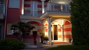A hotel named "HOTEL MEDITERRANEO" with a red facade, multiple balconies, and a well-lit entrance. - Hotel Mediterraneo (Villa Cortese)