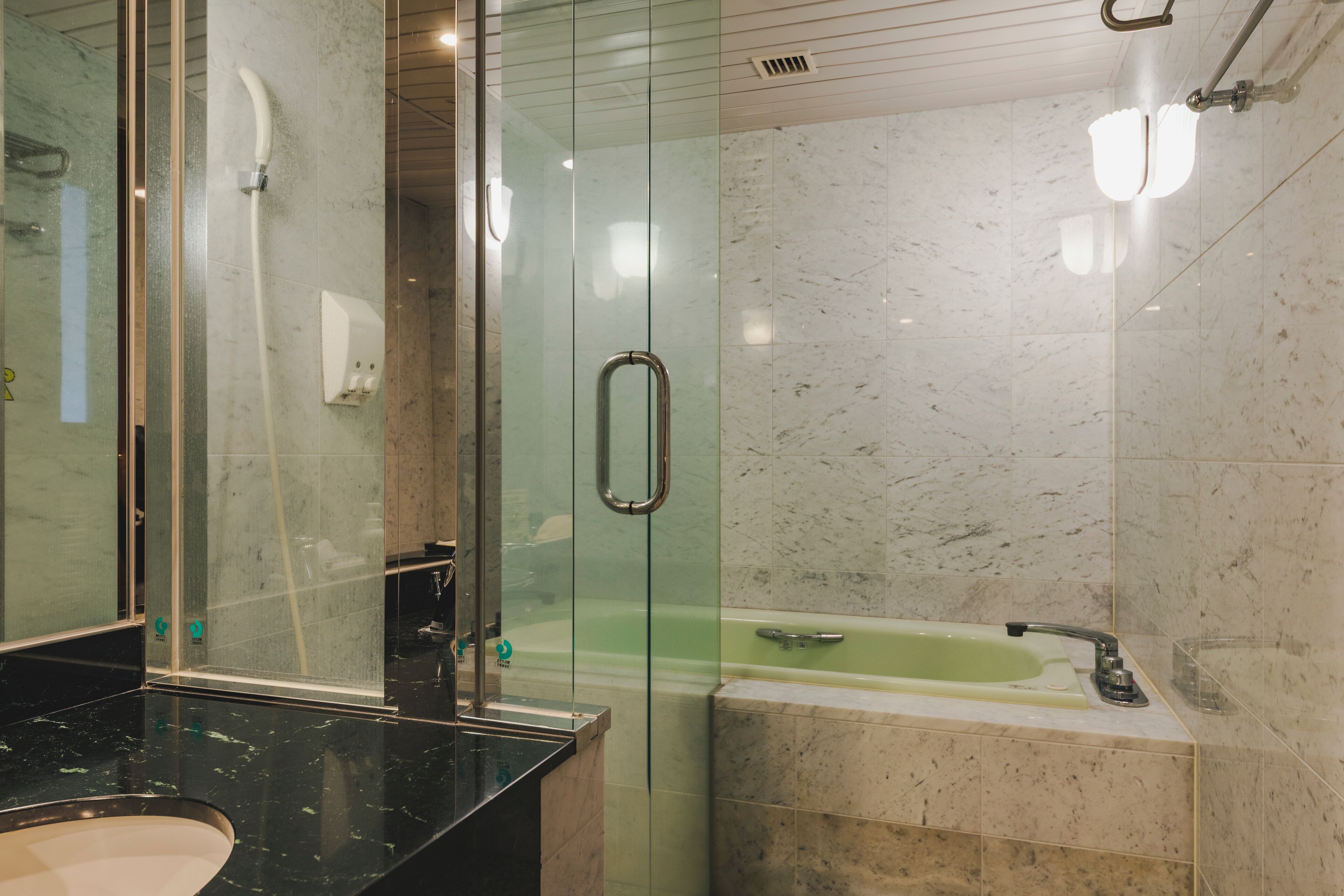 A modern bathroom with a glass-enclosed shower, a freestanding bathtub, and a black marble sink.