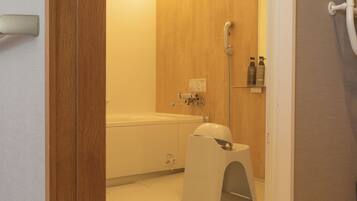 Un baño con tocador de madera, inodoro blanco y zona de ducha.
