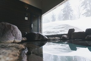 Ein Zimmer mit großem Fenster mit Blick auf eine verschneite Landschaft.