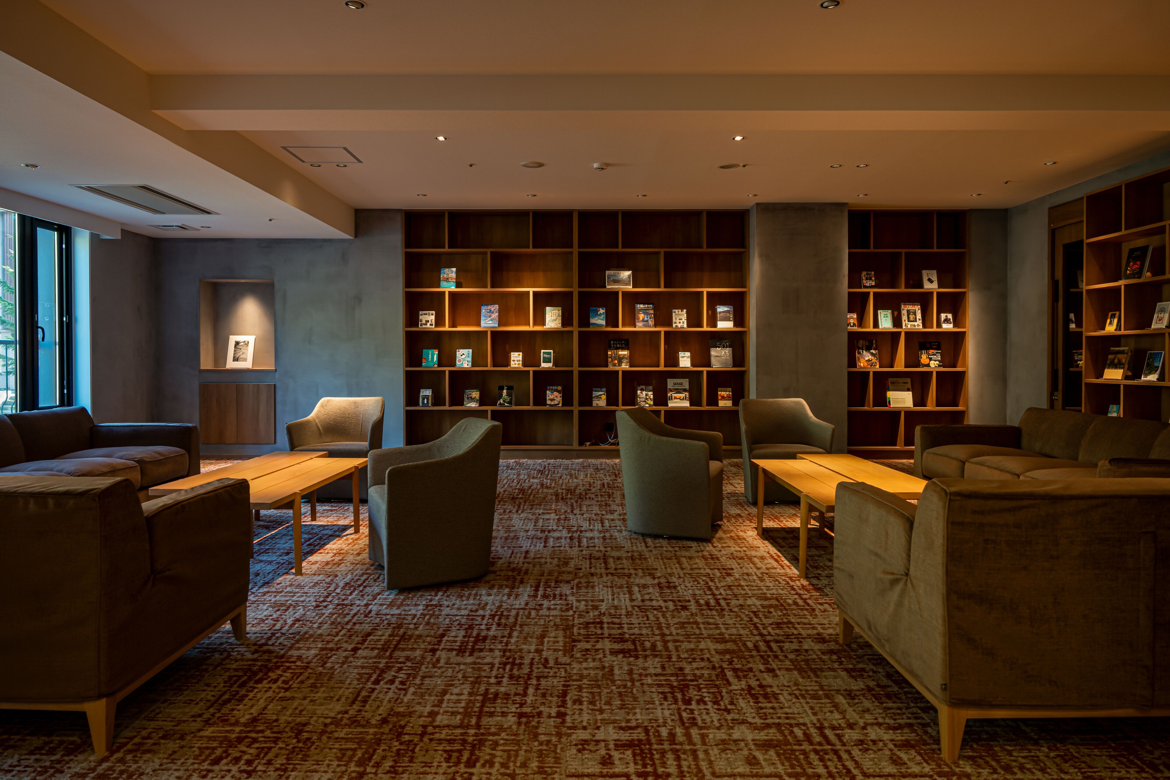 A library with bookshelves, sofas, and a carpeted floor.