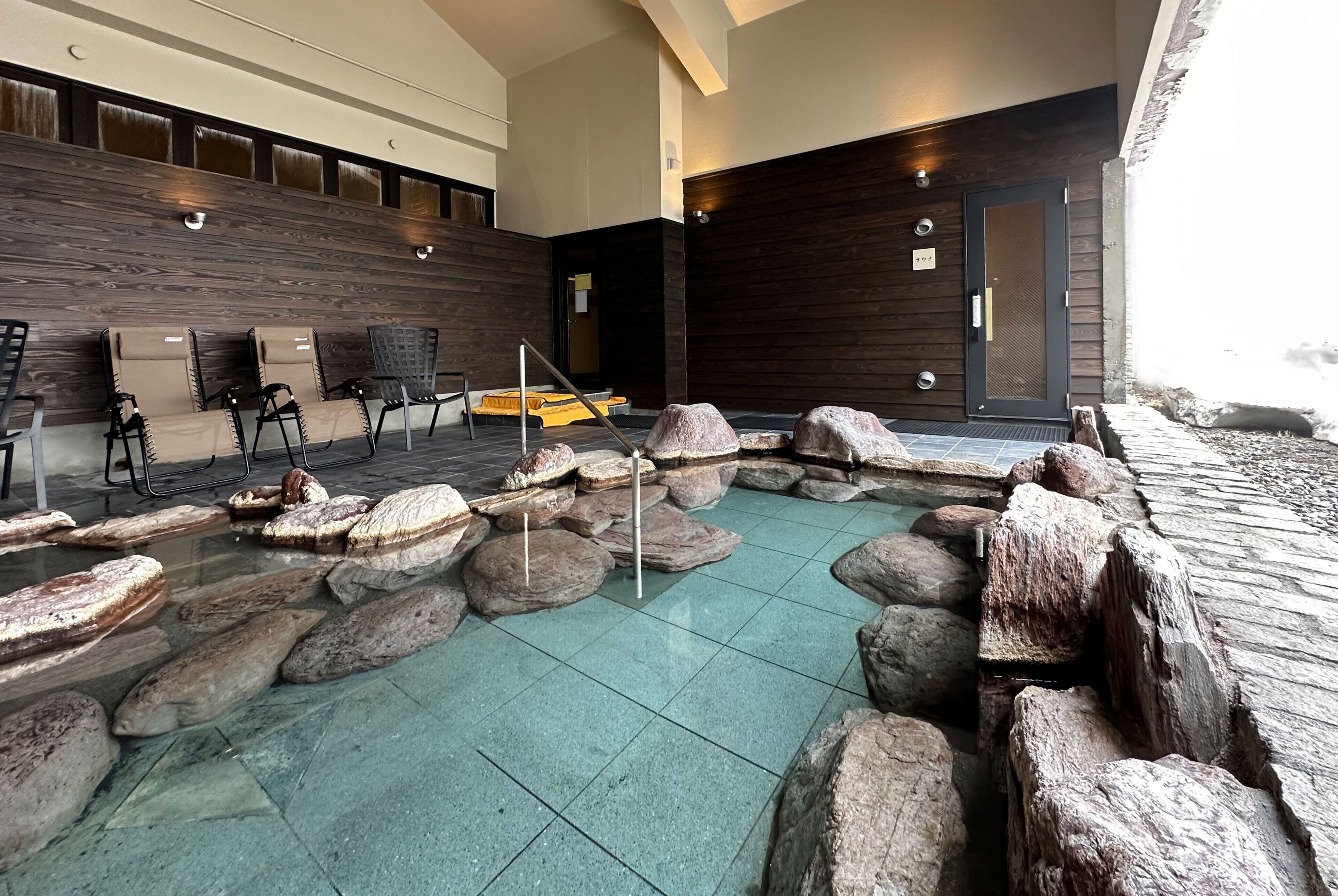 A spa area with a rock garden, seating, and a wooden wall.