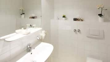 A modern bathroom with white tiles, a large mirror, a sink, and two towel racks.