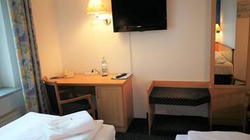 Habitación de hotel con dos camas, un escritorio con silla, televisor y espejo.