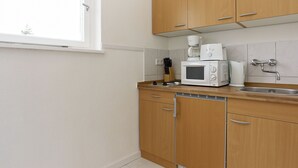 A modern kitchen with wooden cabinets, a microwave, a coffee maker, and a sink.