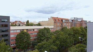 A multi-story building with a mix of residential and commercial spaces, featuring a prominent red brick facade and a modern glass structure.