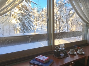 A room with a view of a snowy landscape through a window.