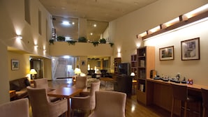 Amplia sala de estar con techo alto, mesa de comedor con sillas, sofá y zona de bar con televisor.