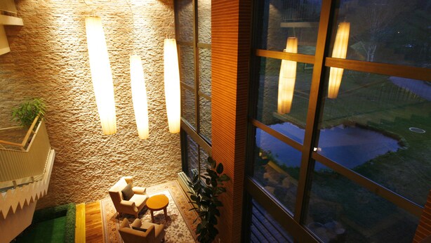 Un rincón acogedor con pared de piedra y ventanas amplias que dan a un estanque.