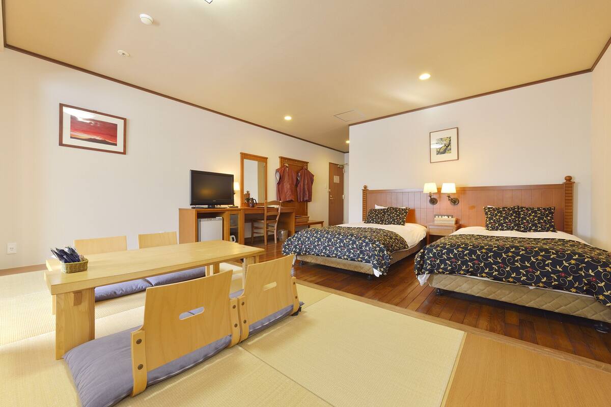 Una habitación de hotel con dos camas, un escritorio con silla, televisor y armario.