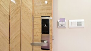 A modern door with a card reader and a wall-mounted light switch. - Hotel Aman International at New Delhi Station (New Delhi)