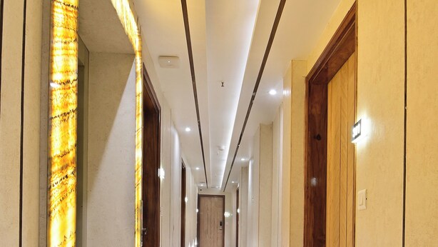 A long, well-lit hallway with marble floors and wooden doors. - Hotel Aman International at New Delhi Station (New Delhi)