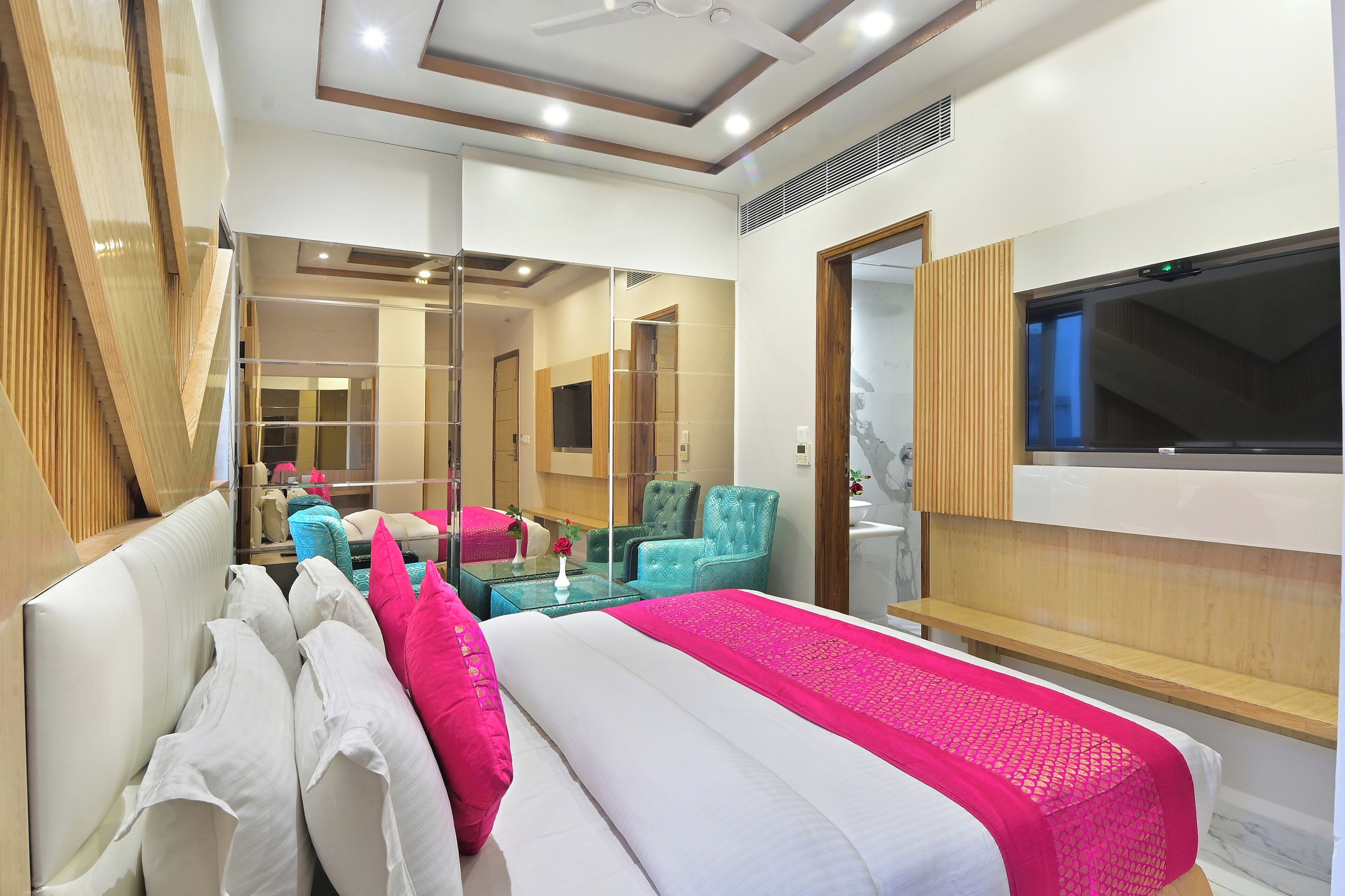 A modern hotel room with a large bed, a TV, and a mirror.
