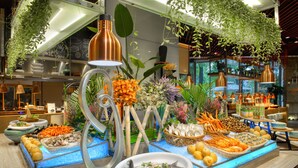 Un bufé con diversos alimentos, como mariscos, frutas y verduras, dispuestos en una mesa con un centro de mesa decorativo.