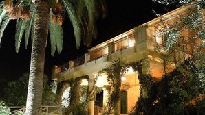 A two-story building with a balcony, surrounded by greenery and illuminated by warm lighting. - Antico Borgo Etneo Country Hotel (Calatabiano)