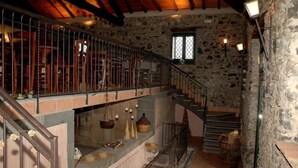 A rustic stone interior with a wooden staircase, a balcony with metal railings, and a stone wall with a window. - Antico Borgo Etneo Country Hotel (Calatabiano)