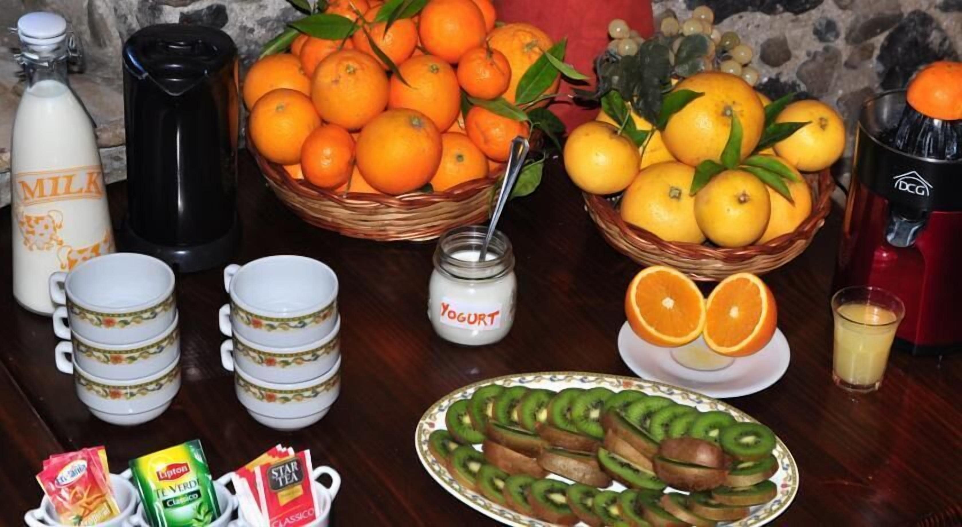 A table with various food items, including oranges, lemons, yogurt, and sliced kiwi.
