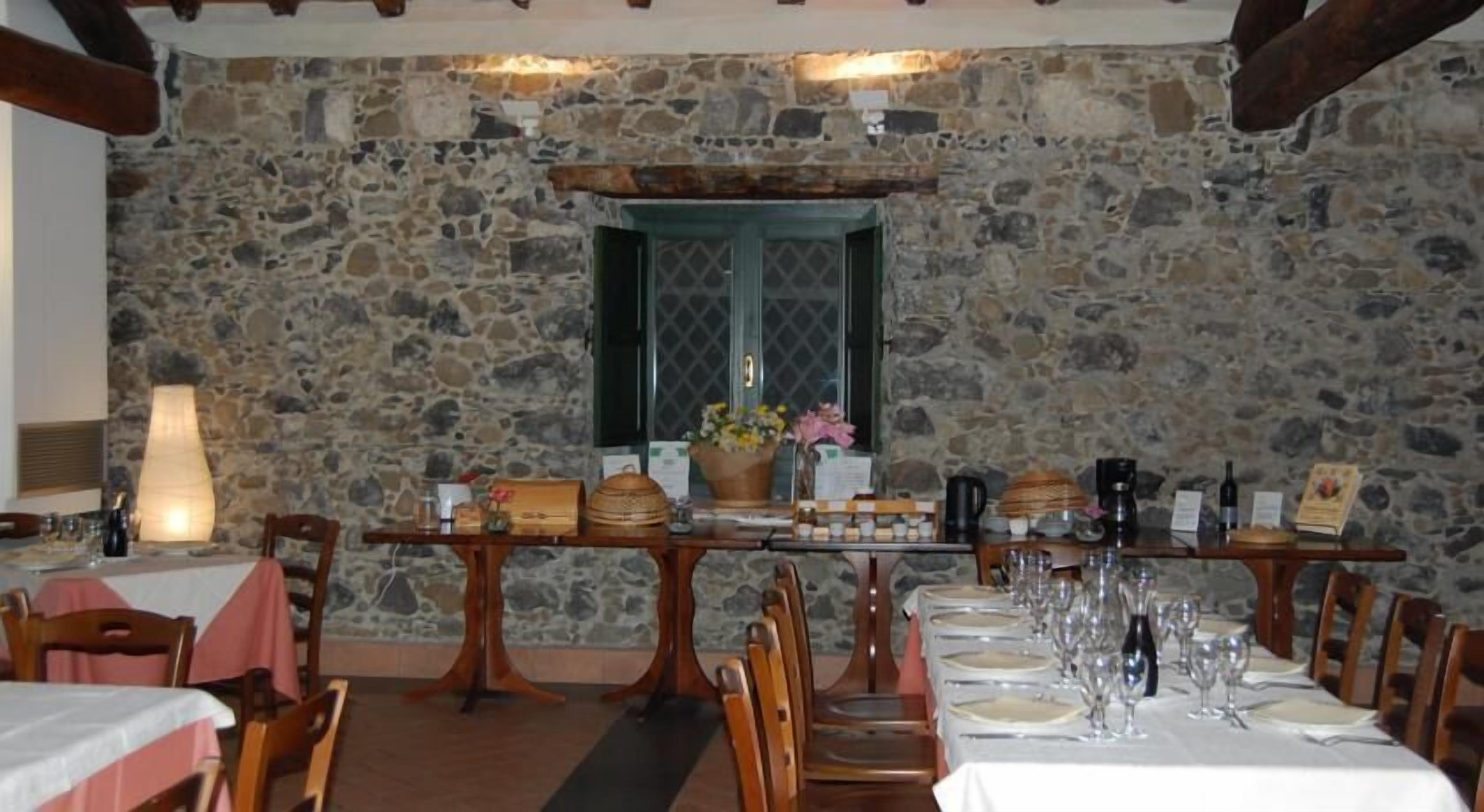 A dining area with stone walls, wooden tables, and chairs.
