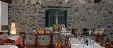 A dining area with stone walls, wooden tables, and chairs.