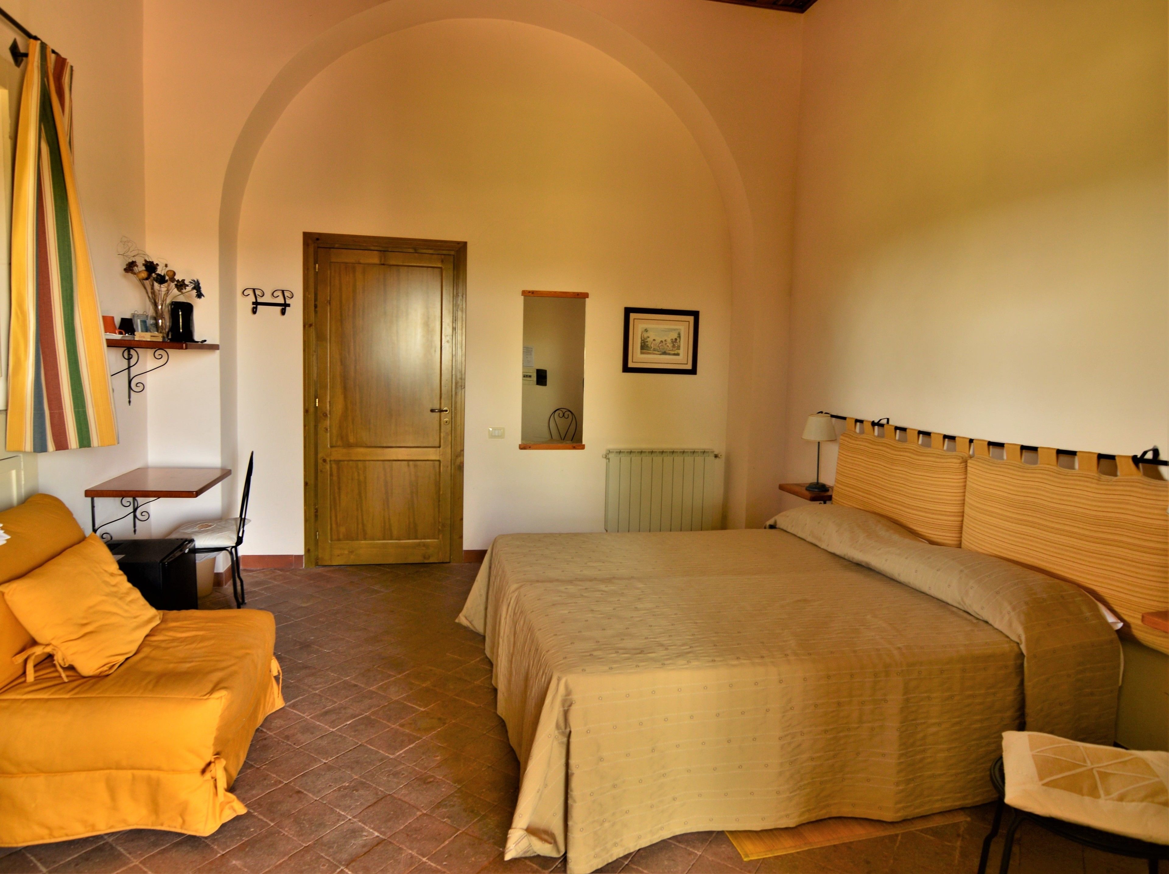 A bedroom with a bed, a chair, a table, and a door.
