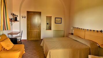 A bedroom with a bed, a chair, a table, and a door.