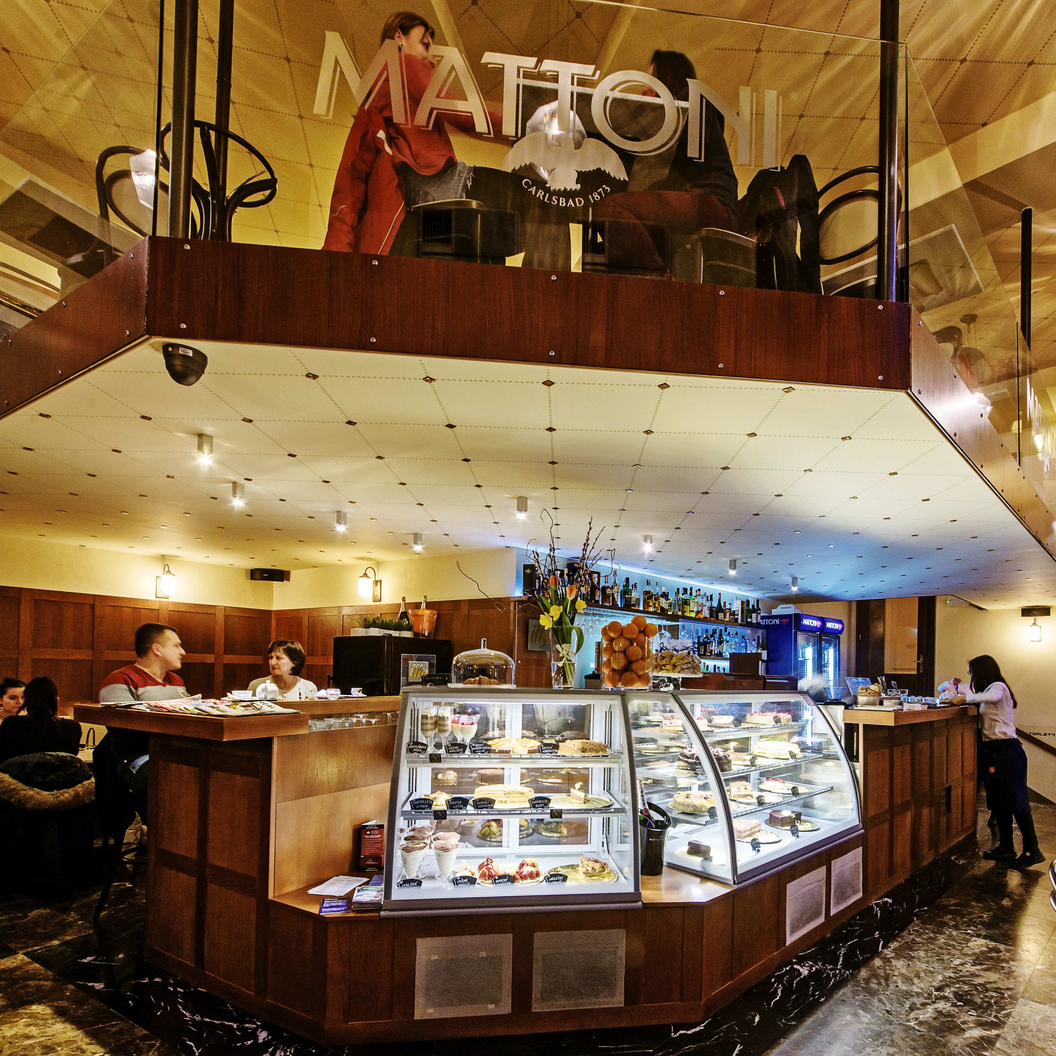 A multi-level hotel lobby with a bar area, a display case with desserts, and a seating area.