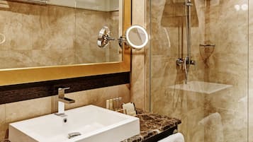 Un baño moderno con un espejo grande, un lavabo blanco, una ducha con cerramiento de vidrio y una encimera de mármol.