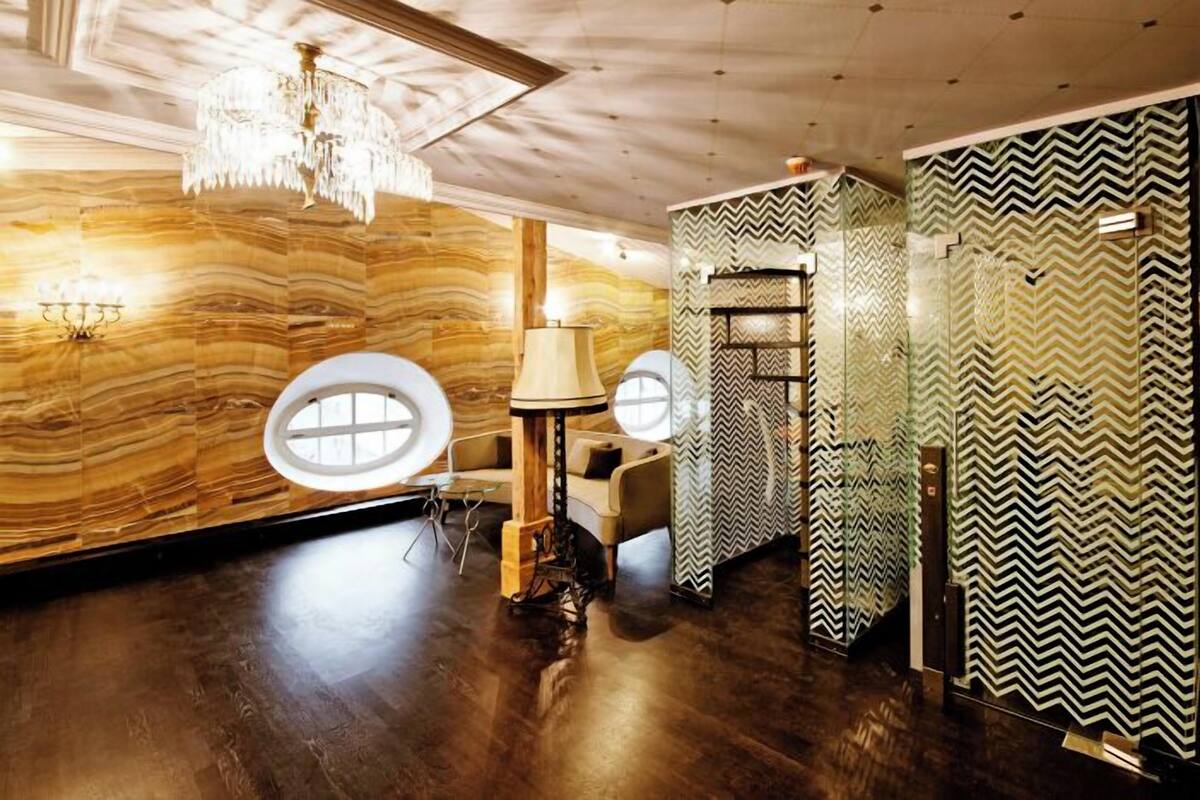 Ein Zimmer mit Holzboden, einem Chandelier, einem runden Fenster und einem Spiegel mit Zickzackmuster.