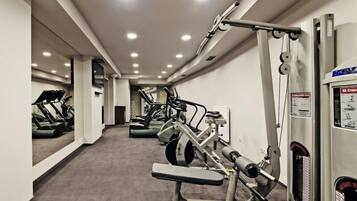 Un gimnasio con cintas de correr, elípticas y equipo de levantamiento de pesas.