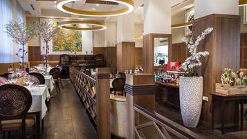 A restaurant with wooden decor, a central bar, and a large floral arrangement.