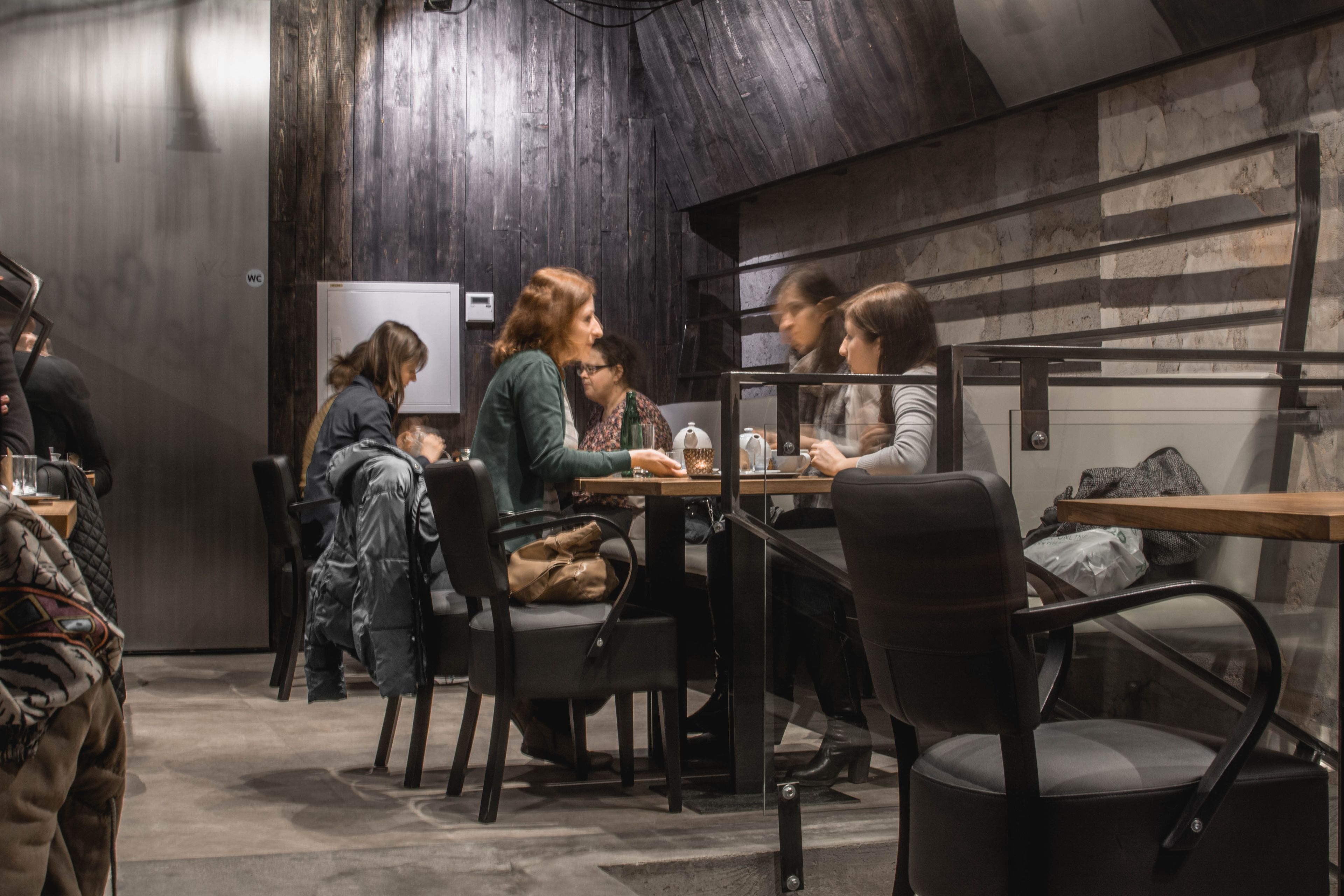 A modern interior with wooden walls and a sloped ceiling, featuring tables and chairs arranged for dining or meetings.