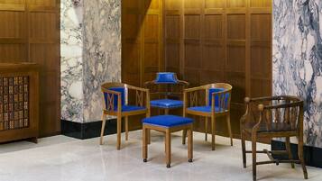 A room with a marble wall, wooden paneling, and a small table with four blue chairs.