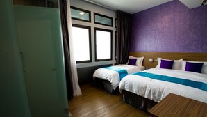 A hotel room with two beds, a wooden headboard, a window with curtains, and a wooden floor.