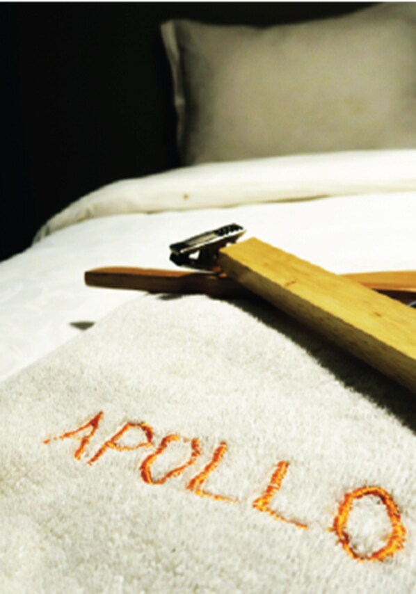 A bed with a white blanket and a wooden hanger on it.